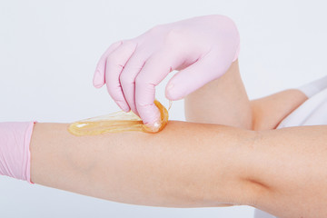 Hands in rubber gloves close-up. doctor puts wax, honey. medic is preparing for depilation. Concept of medicine, medical instruments, health care, beauty industry, hair removal, natural material