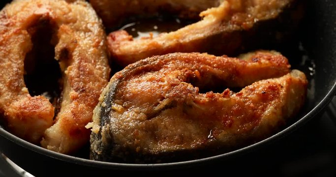 Carp, frying carp divided into portions, breaded in breadcrumbs and flour in a pan, close-up, 4K. Traditional Christmas Eve dish