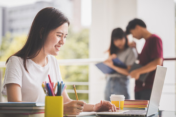 Education of university concept -Young female students are relaxing by sitting on the smart phone after reading a book.