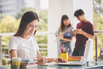 Education of university concept -Young female students are relaxing by sitting on the smart phone after reading a book.