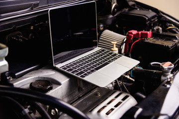 Laptop computer on car mechanic engine for service