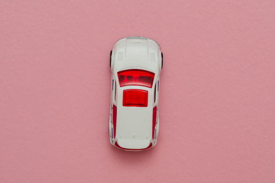 White Model Of A Toy Car On A Pink Background. View From Above