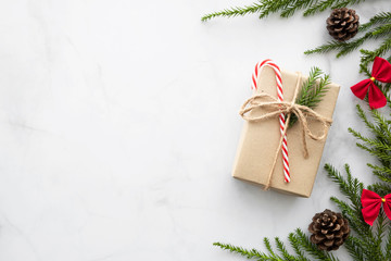 White marble table with Christmas decoration including giftbox, candy cane, pine branches and pine...