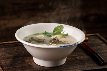 Shrimp wonton with braised pork in soup on wooden table / Select focus image...