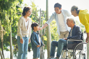 happy asian multi generation family relaxing outdoors