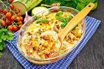 Zucchini baked with tomatoes in glass pan on board