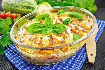 Zucchini baked with tomatoes in pan on dark board