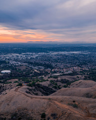 Aerial view of open rolling hills in suburban Southern California.  Radio tower atop hill during sunset surrounded by mountains and ocean