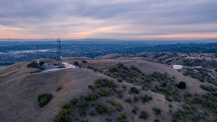 Aerial view of open rolling hills in suburban Southern California.  Radio tower atop hill during...