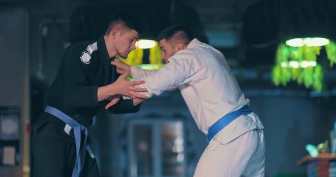 Judo fighters continue to fight, the fighter makes a leg sweep and the enemy falls. Judokas do receptions on the floor, receptions in the parterre.