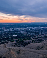 Obraz premium Aerial view of open rolling hills in suburban Southern California. Radio tower atop hill during sunset surrounded by mountains and ocean