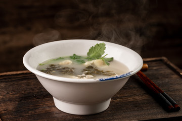 Shrimp wonton with braised pork in soup on wooden table / Select focus image...