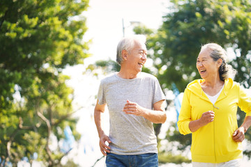 happy chinese senior couple running outdoors