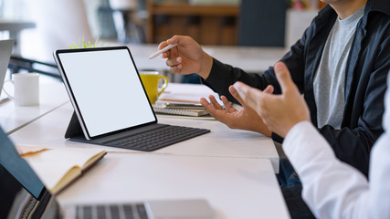 Mockup blank white desktop screen tablet with a man and woman are working in background.