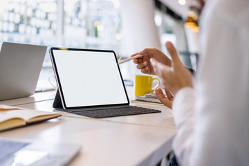 Mockup blank white desktop screen tablet with a man and woman are working in background.