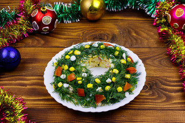 Fototapeta na wymiar Salad Christmas wreath and Christmas decorations on a wooden table