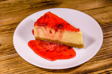 White plate with cheesecake New York and raspberry jam on wooden table