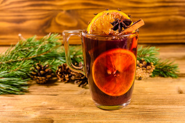Cup of mulled wine with cinnamon and fir tree branches on wooden table