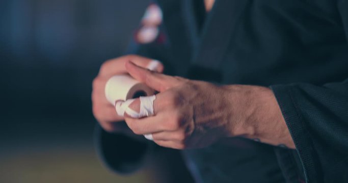 Wrestler wraps his fingers with a bandage before the fight. Hand protection for athletes fighters. Close-up.
