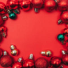 Red Christmas balls frame on red background with copy space in centre. Flat lay. unfocused.