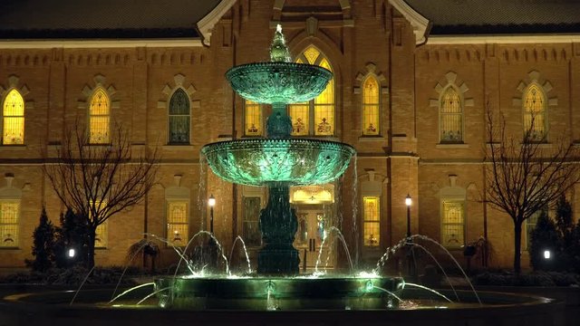 View of fountain flowing at night by temple in Provo as it lightly snows.