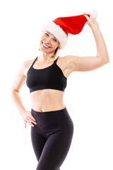 Young smiling woman in santa claus hat and in black fitness suit. Isolated over white background. Festive mood. Vertical.