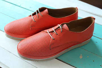 Naklejka premium fashionable leather orange flat shoes on a wooden stand