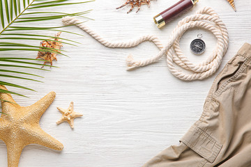 Set of travel accessories with clothes and starfishes on white wooden background