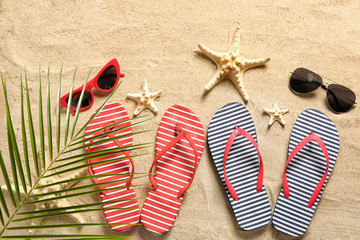 Stylish flip-flops with sunglasses and starfishes on sand