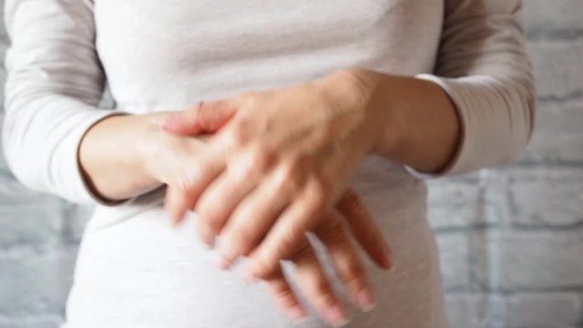European woman applying smears moisturizes hands with cosmetic cream. Rubs the cream in his hands.