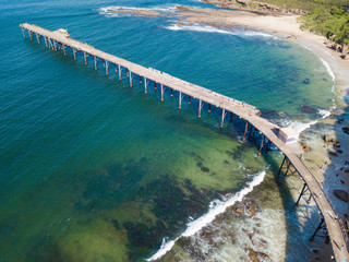 Aerial view of a jetty above turquoise water beach.