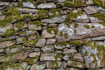 an old manmade stone wall with moss on it