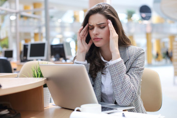 Frustrated business woman looking exhausted while sitting at her working place