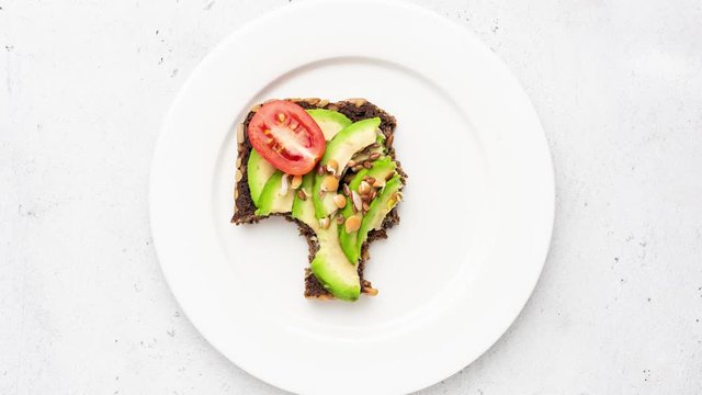 Stop motion animation of eating vegan food avocado toast bite by bite. Top view. Healthy eating concept