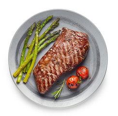 Cooked Beef steak on grey plate with asparagus and rosemary on white background