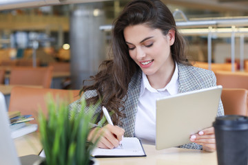 Portrait of a pretty female student with laptop in library.