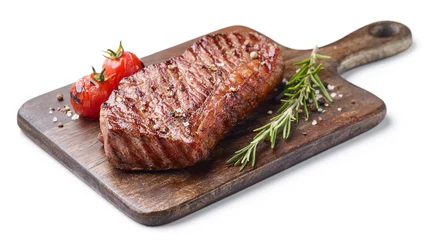 Tuinposter Grilled beef steak on wooden board isolated on white background with tomatoes and rosemary © Karlis