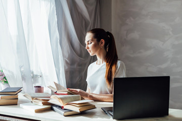 girl works at the computer reads books