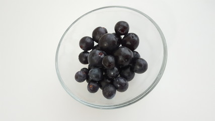 black grapes in glass bowl on white background