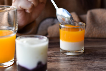 Orange flavored yogurt in glass shot on wooden table.