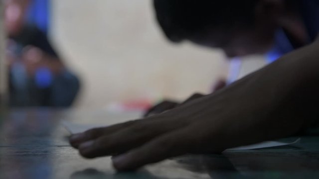 close up of the hands of a man compiling a check in Cambodia