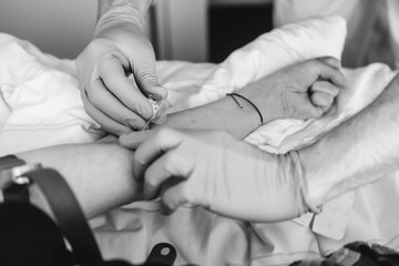 Arzt sticht mit Nadel in die Ader im Arm eines Patient
