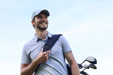 Golf player walking and carrying bag on course during summer game golfing.