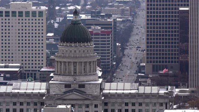 Traffic on State Street in downtown Salt Lake City past the Capitol building as flag waves on top.