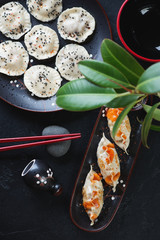 Above view of potstickers and boiled asian dumplings over black stone background, vertical shot