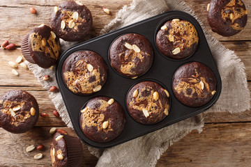 Homemade chocolate muffins with peanut butter and nuts in a baking dish. Horizontal top view