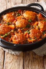Delicious meatballs stewed with lentils and vegetables close-up in a pan on the table. vertical