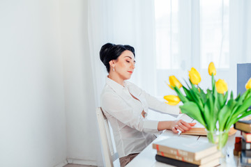 women in a business suit behind a table with books