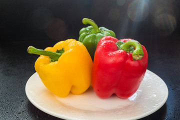 colorful bell peppers on white plate covered water drops lens flare light effect