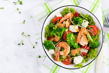 Delicious fresh salad with shrimps / prawns, broccoli, feta cheese, tomatoes, lettuce and peanut dressing. Diet menu. Top view, copy space